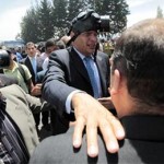 Rafael Correa es protegido del gas lacrimógeno durante una protesta de efectivos policiales en el Regimiento de Policía Número 1 de Quito. Foto: EFE.
